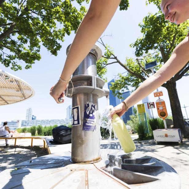 Wasserflasche wird an einem heißen Tag an einem Trinkbrunnen aufgefüllt.