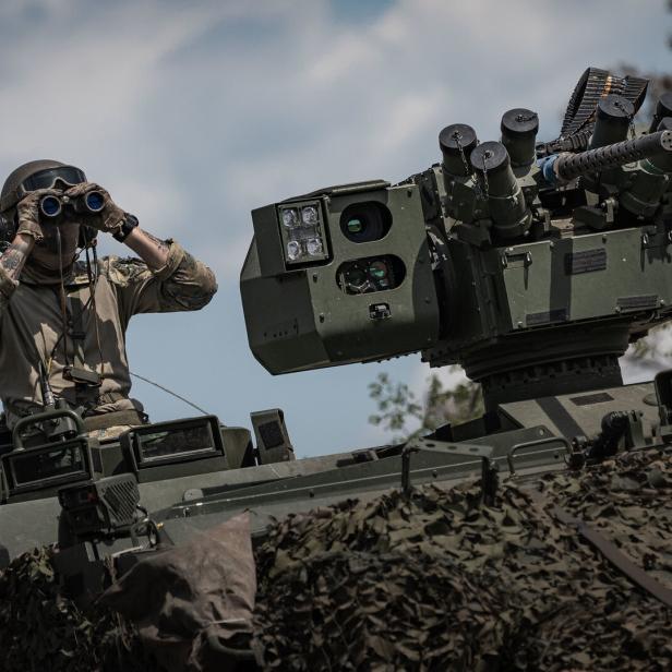 Soldat mit Feldstecher sitzt auf einem Panzer