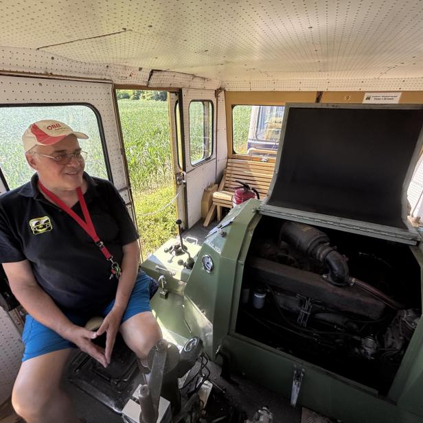 Mann sitzt in einem Zug mit einem historischen Motor.