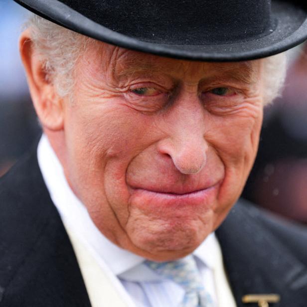 König Charles III. trägt einen schwarzen Zylinder und einen dunklen Anzug.