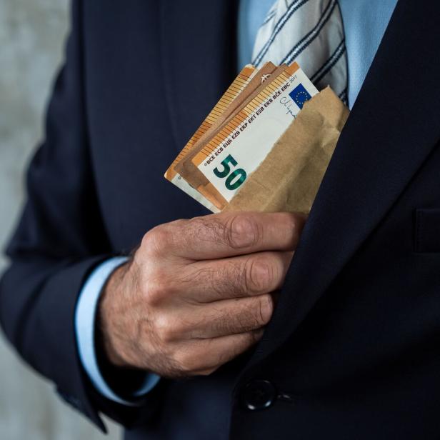 Man in Suit Concealing Cash in Envelope