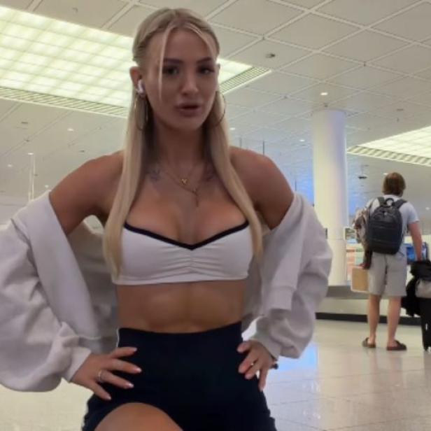 Edda Pilz posiert im Flughafen in Sport-BH und Shorts, bevor sie von Lufthansa wegen ihres Outfits am Boarding gehindert wurde.