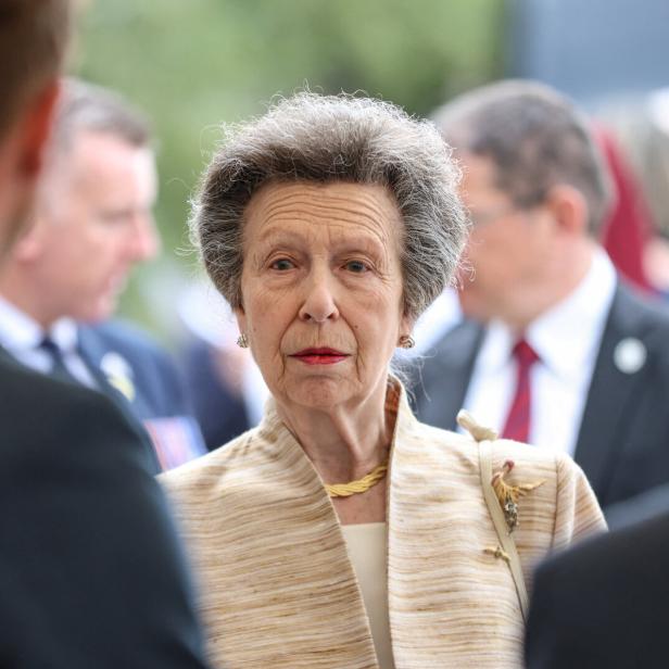 Prinzessin Anne trägt eine beige Jacke und blickt ernst in einer Menschenmenge umher.