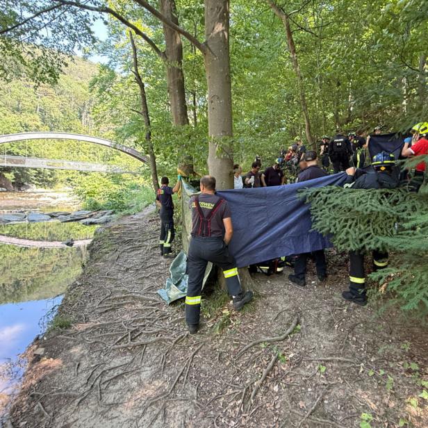 Feuerwehrleute schirmen eine Unfallstelle neben einem Fluß ab
