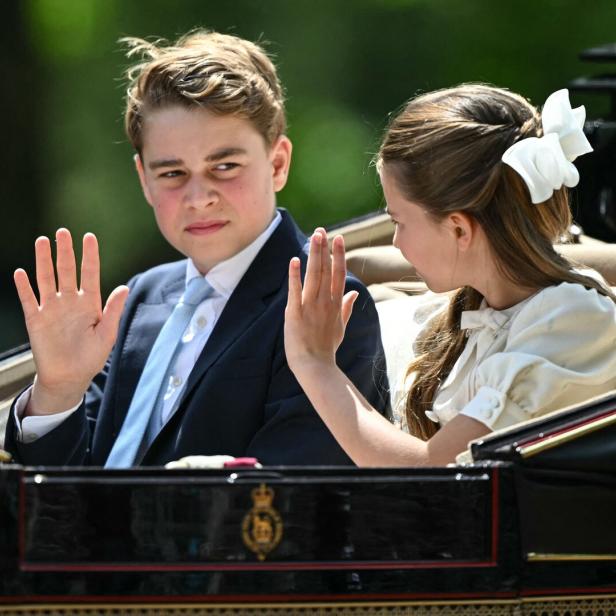 Prinz George und Prinzessin Charlotte winken in einer Kutsche sitzend der Menge zu.