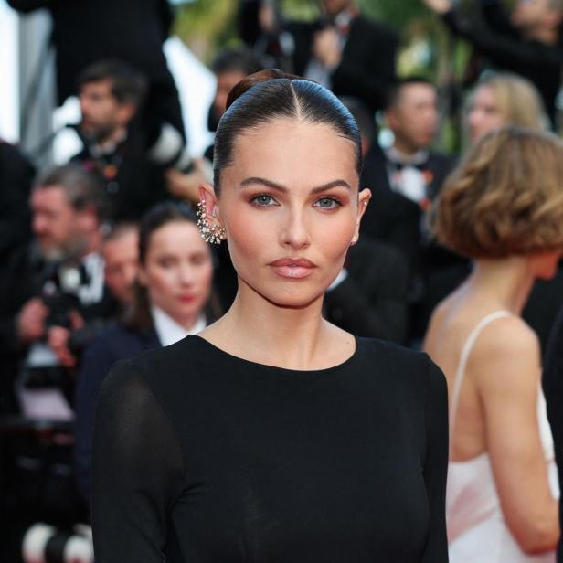 Thylane Blondeau trägt ein elegantes schwarzes Kleid und auffälligen Ohrschmuck auf dem roten Teppich.