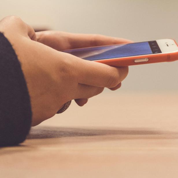 Hände halten ein Smartphone mit geöffnetem Social-Media-Post.