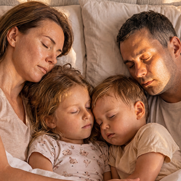 Eine Familie schläft eng aneinander gekuschelt im Bett.