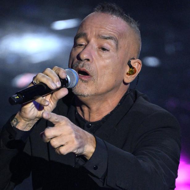 Eros Ramazzotti singt in ein Mikrofon und zeigt mit dem Finger in die Menge.