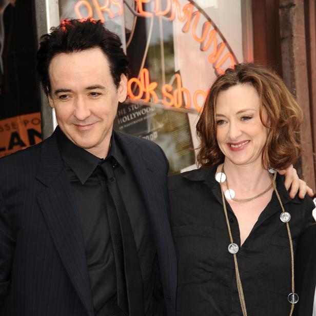 John und Joan Cusack lächeln gemeinsam vor einem Kinoeingang bei einer Veranstaltung.