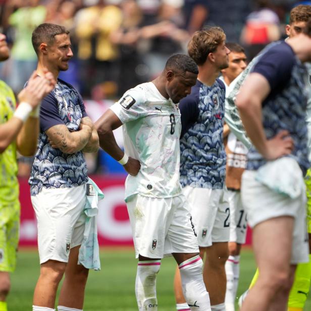 Spieler der österreichischen Fußballnationalmannschaft stehen enttäuscht auf dem Rasen.
