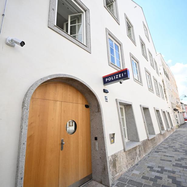 Weiße Polizeistation mit Holzportal und mehreren Fenstern an einer gepflasterten Gasse.