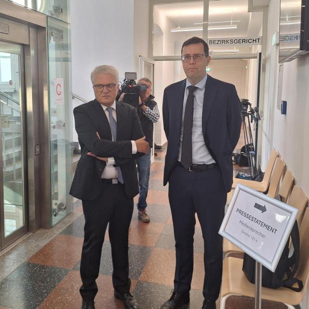 Zwei Männer in Anzügen vor einem Gerichtssaal
