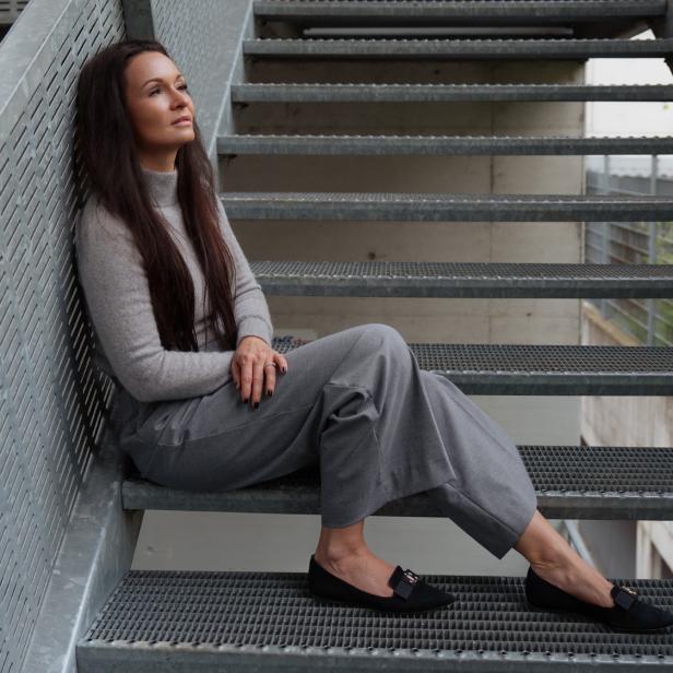 Frau sitzt auf einer Metalltreppe.