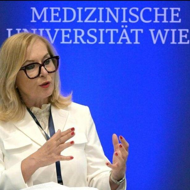 Eine Frau in weißem Blazer spricht an einem Stehpult vor dem Schriftzug „Medizinische Universität Wien“.