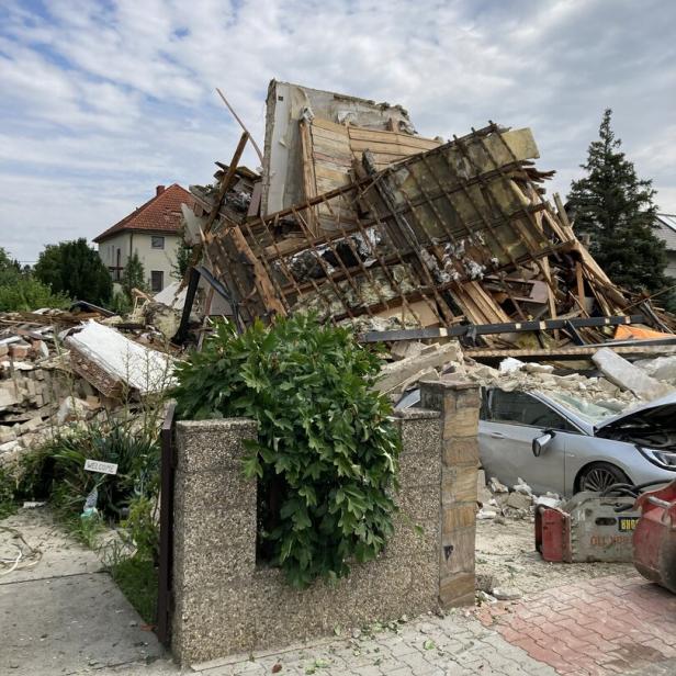 Ein eingestürztes Gebäude liegt in Trümmern, wobei ein silbernes Auto unter den Überresten begraben wurde.