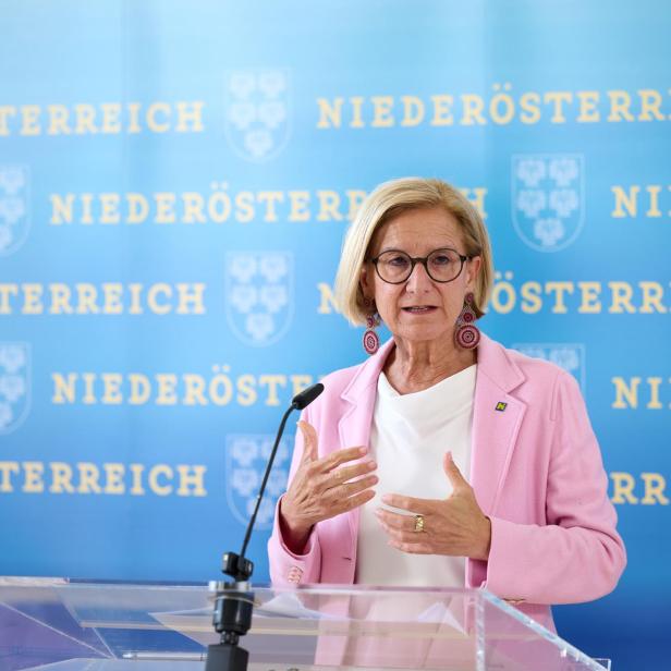 Johanna Mikl-Leitner steht vor einem Rednerpult und spricht in ein Mikrofon, hinter ihr ist eine blaue Wand, auf der mit gelben Buchstaben Niederösterreich steht