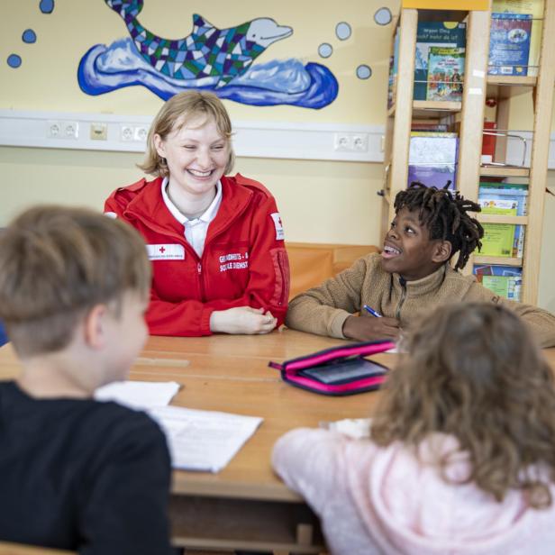 Kinder bekommen Unterstützung beim Lernen durch eine Mitarbeiterin des Österreichischen Roten Kreuz