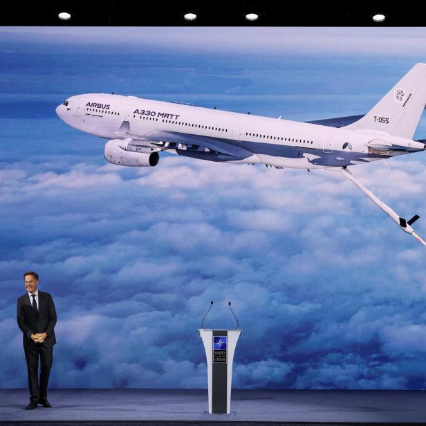 Zwei Männer vor NATO-Pult, darüber ein Airbus A330 MRTT über den Wolken.