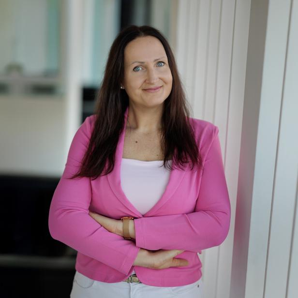 Frau im pinken Blazer mit verschränkten Armen