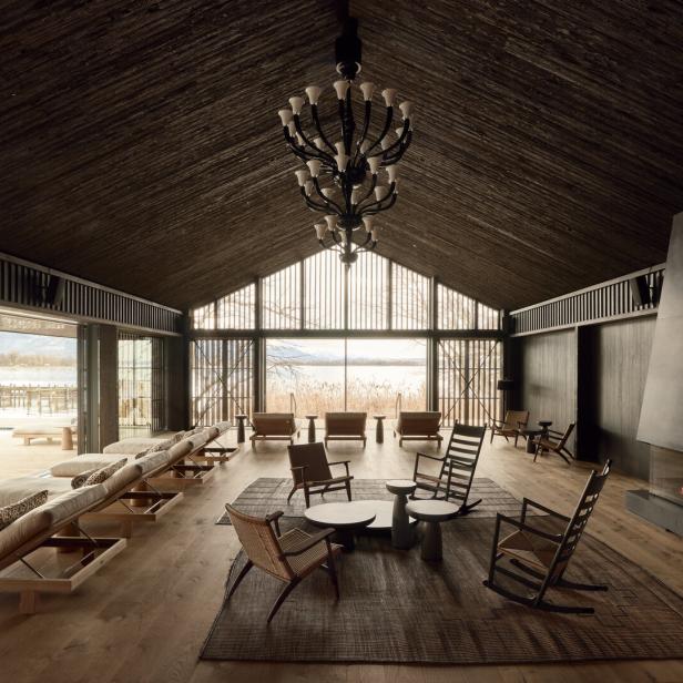 ein hotel mit deckenhohen Fenstern und Sesseln und Tischen aus Holz davor