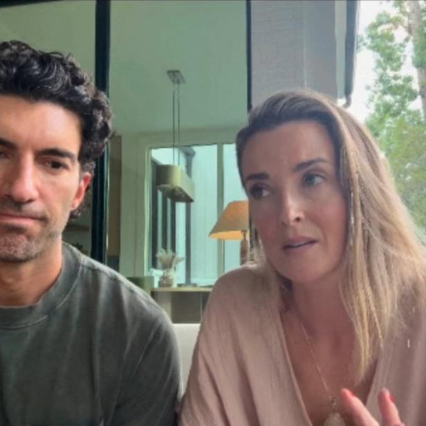 Justin Baldoni mit dunklen Locken und seine Emily Baldoni mit blondem Haar sitzen nebeneinander und sprechen in die Kamera.