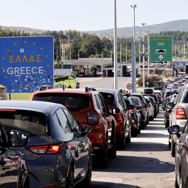 Autoschlange vor dem Grenzübergang nach Griechenland mit Schildern und Stau.