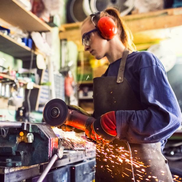Young woman cutting iron bar in workshop