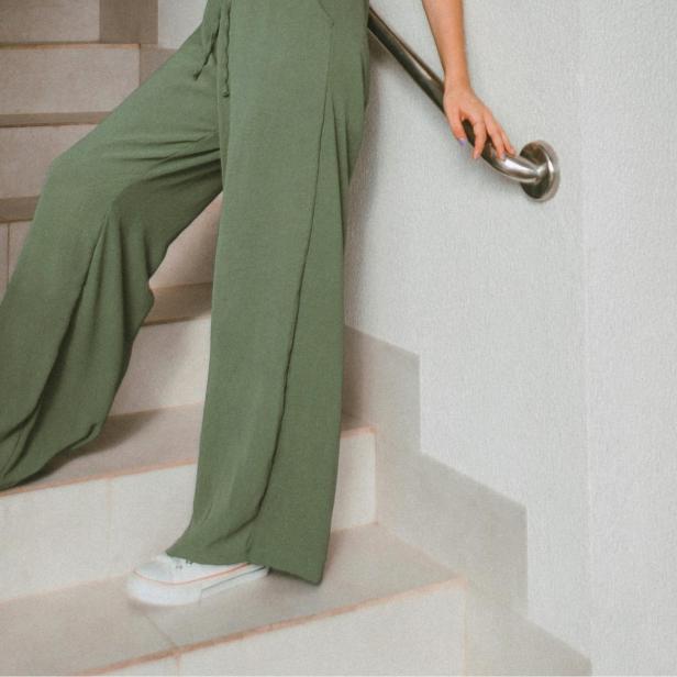 Frau mit olivfarbener weiter Stoffhose steht auf einer Treppe