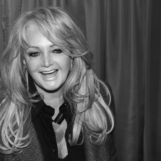 Bonnie Tyler lächelt in die Kamera vor einem dunklen Vorhang.