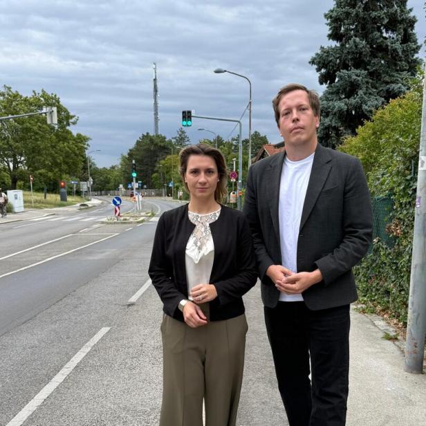 Johanna Zinkl und Patrick Gasselich stehen an einer Straße bei grüner Ampel unter bedecktem Himmel.