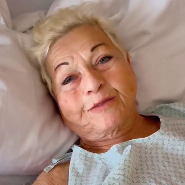 Jazz Gitti liegt im Krankenhausbett im OP-Hemd und blickt in die Kamera.