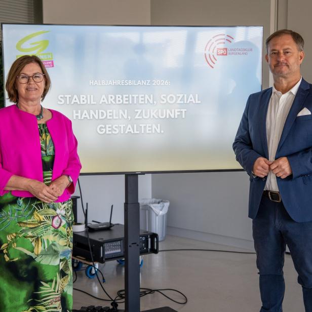 Zwei Politiker stehen vor einer Tafel mit der Aufschrift „Halbjahresbilanz 2026“.