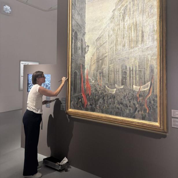 Eine Frau restauriert ein großes historisches Gemälde im Museum.