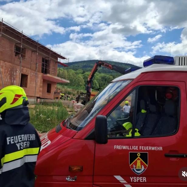 Feuerwehr und Rettungskräfte an einer Baustelle mit Einsatzfahrzeug und Kran.