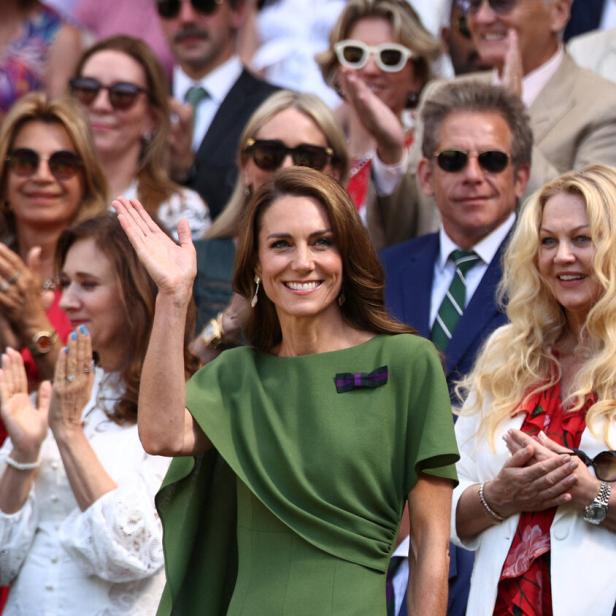 Prinzessin Kate winkt lächelnd in einem grünen Kleid in die Menge, während weitere Zuschauer im Hintergrund applaudieren.