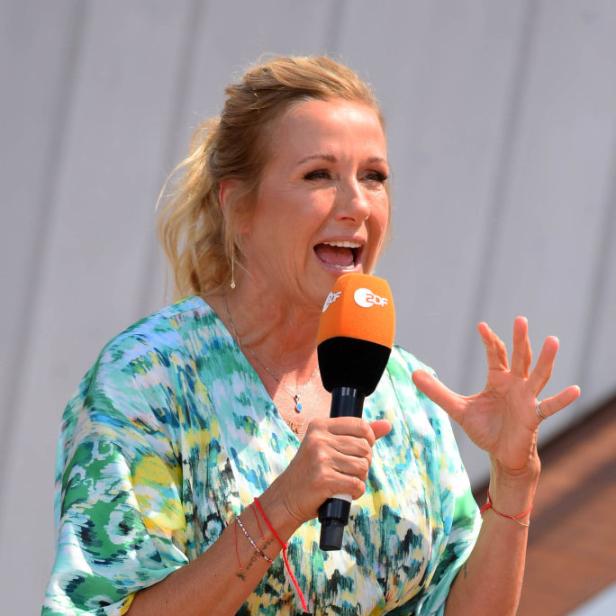 Andrea Kiewel spricht beim ZDF-„Fernsehgarten“ mit Mikrofon in der Hand.