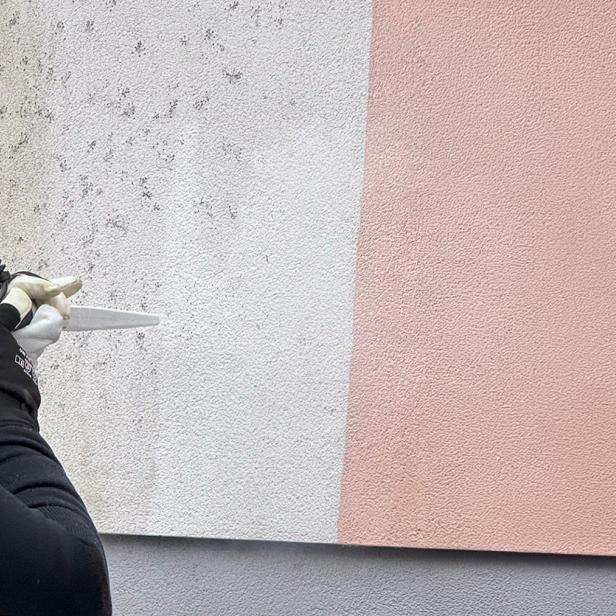 Person reinigt eine Hausfassade mit einem Trockeneisstrahlgerät.