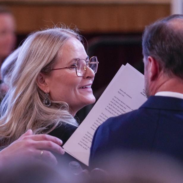 Kronprinzessin Mette-Marit von Norwegen lächelt ihrem Ehemann Kronprinz Haakon zu, während sie gemeinsam ein Blatt Papier mit Text lesen.