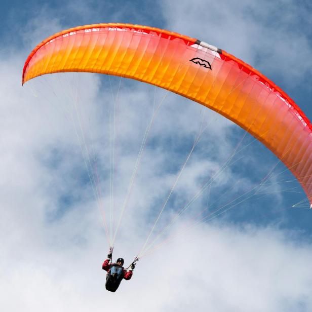 Mann fliegt mit Gleitschirm durch den Himmel