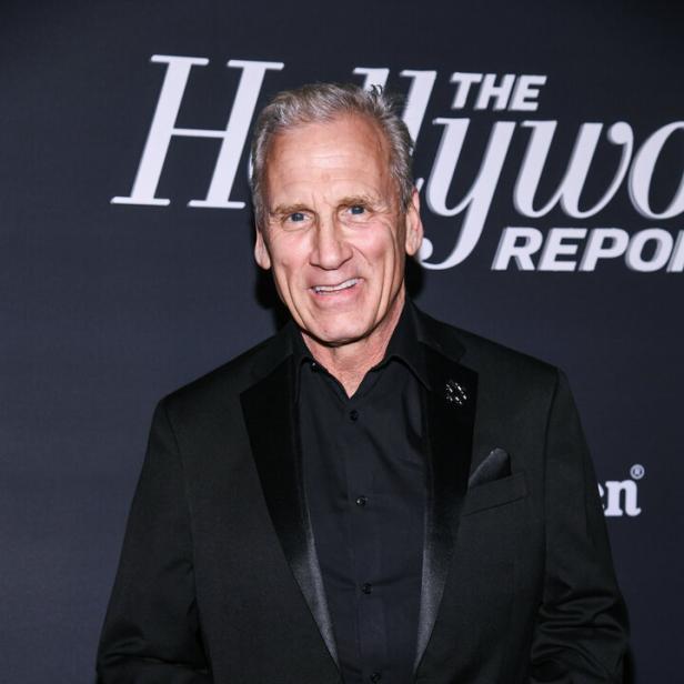 Der Schauspieler Will Roberts lächelt vor einem Hintergrund von The Hollywood Reporter in einem schwarzen Anzug.