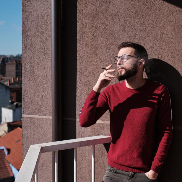 Mann raucht am Balkon