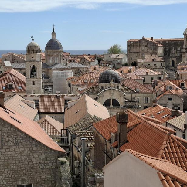 Blick über die Altstadt von Dubrovnik mit ihren charakteristischen roten Ziegeldächern und historischen Steingebäuden vor dem blauen Meer.