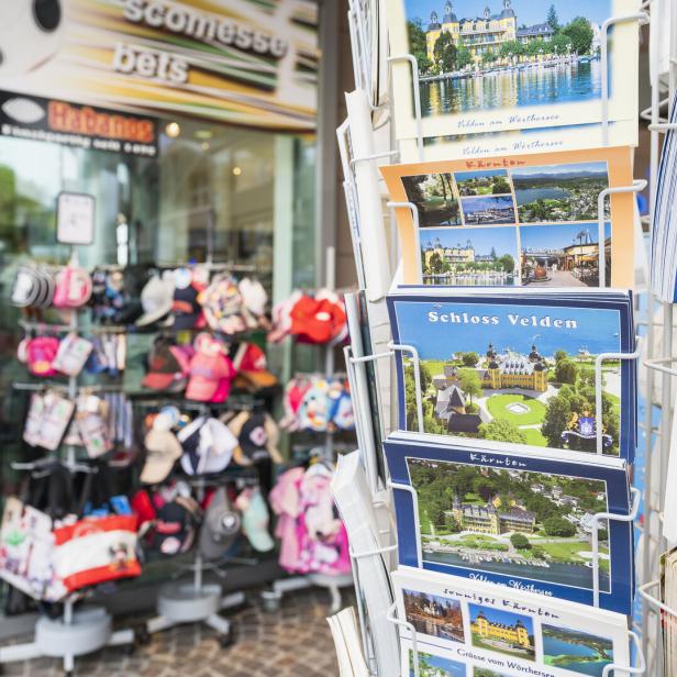 Postkartenständer vor einem Souvenirshop mit Ansichten vom Wörthersee und Schloss Velden.