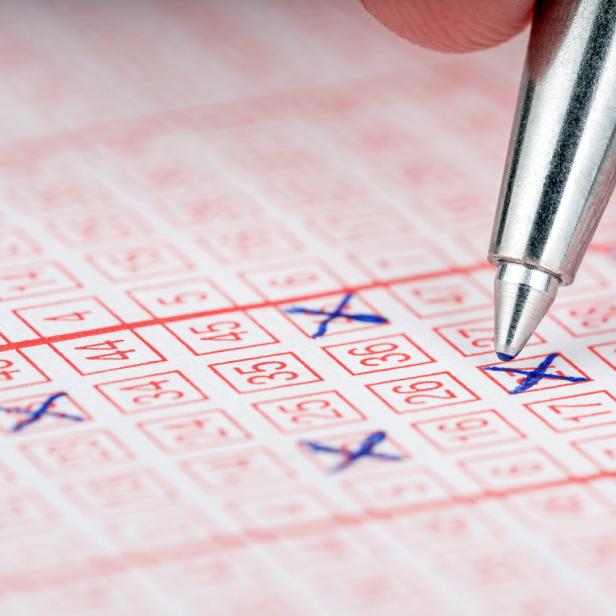Close-up of a pen marking numbers on a lottery ticket.