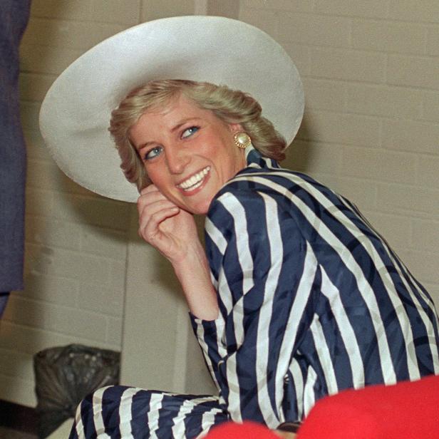 Prinzessin Diana lächelt in einem blau-weiß gestreiften Kostüm und einem passenden weißen Hut.
