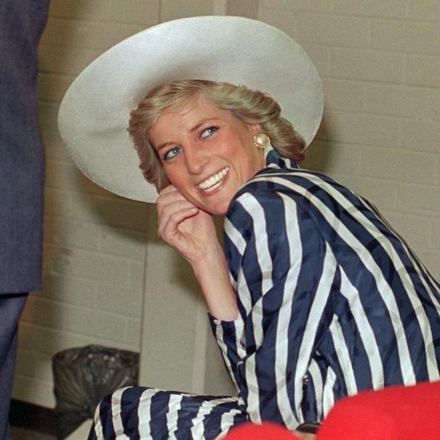 Prinzessin Diana lächelt in einem blau-weiß gestreiften Kostüm und einem passenden weißen Hut.