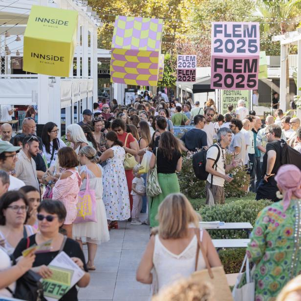 Menschenmenge auf einem literarischen Festival mit FLEM-2025-Bannern im Freien.