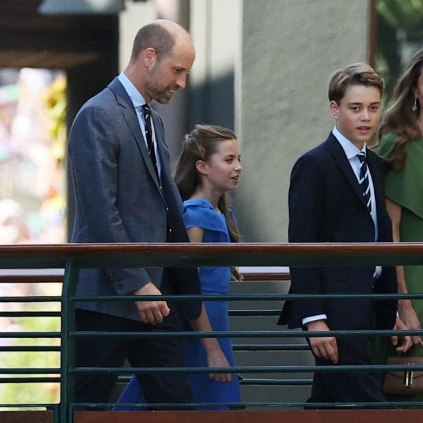 Prinz William, Prinzessin Kate, Prinz George und Prinzessin Charlotte gehen gemeinsam an einem Geländer entlang.