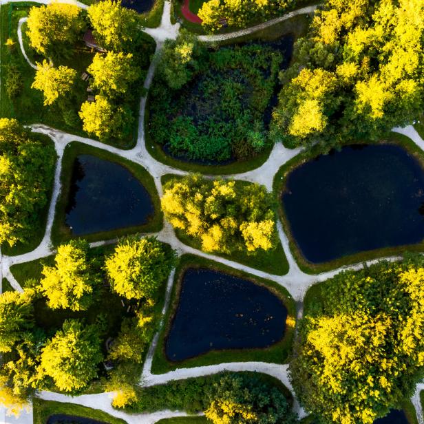 Luftaufnahme des Lakeside Science & Technology Park in Klagenfurt mit Wegen, Teichen und Gebäuden.